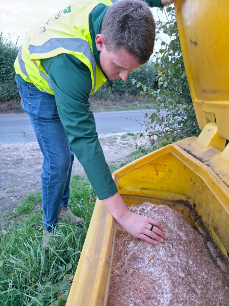 ProLand inspector checking the contents of an open yellow grit bin